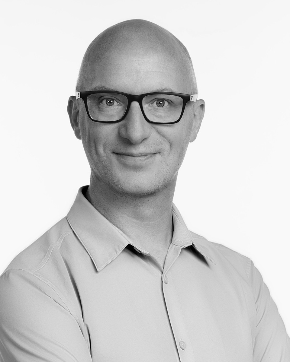 Portrait of Jack Shute, smiling, wearing glasses and a light shirt